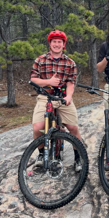 Male student on bike giving thumbs up.