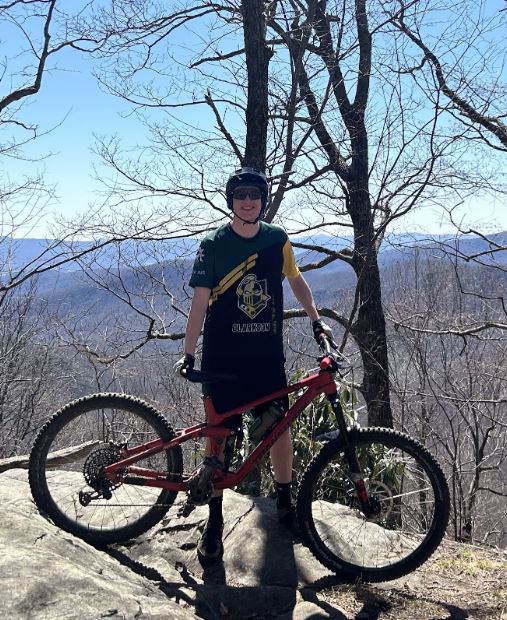 Male student standing by mountain bike.